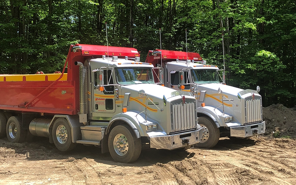 Two work trucks parked at an excavation site