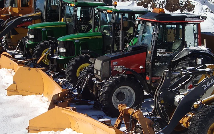 Row of tractors and loaders parked in the snow, ready for snow removal